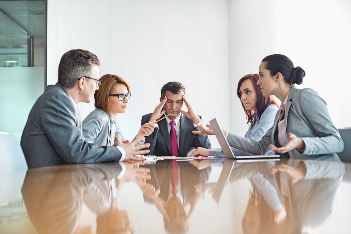 Executive leadership team discussing information security and compliance challenges during high-pressure meeting.